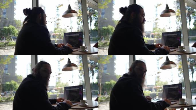 一个中年男子在咖啡店用笔记本电脑工作的肖像