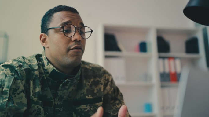 经验丰富的非裔美国军事导师在笔记本电脑上解释在线材料