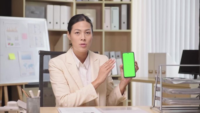 女企业家向镜头展示带有绿色色度键屏的智能手机