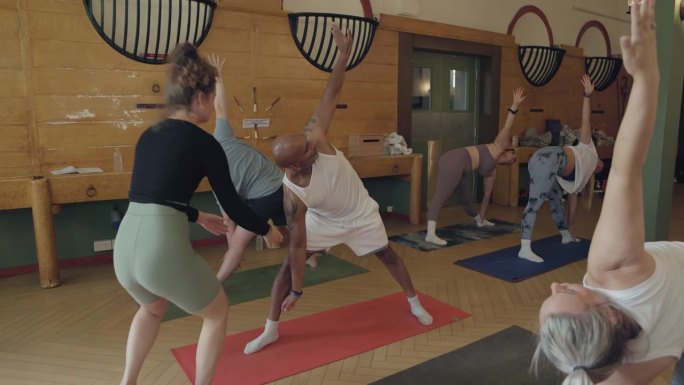 瑜伽，平衡和人们在课堂上与教练进行健康，伸展和健康锻炼。健身，正念和一群男人和女人在体操垫上锻炼，普