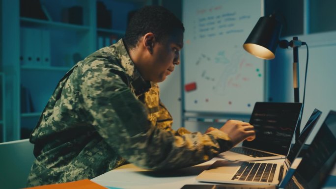 非裔美国情报官员在办公室打笔记本电脑，策划策略