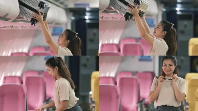 一位亚洲女游客将她的行李箱放在飞机内的架子上。