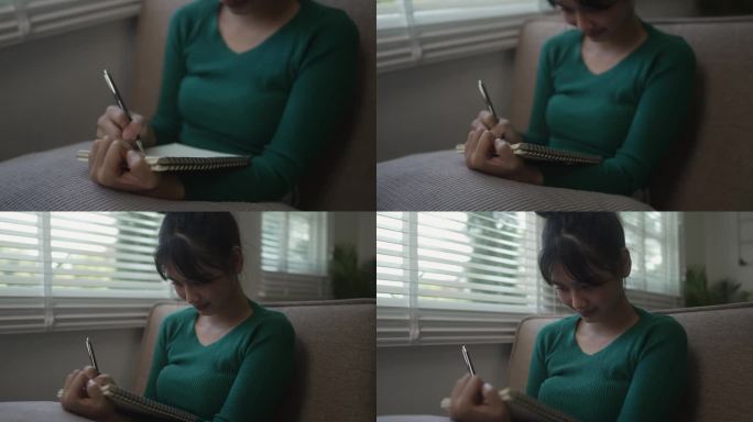 亚洲女性在家里用笔记本写字