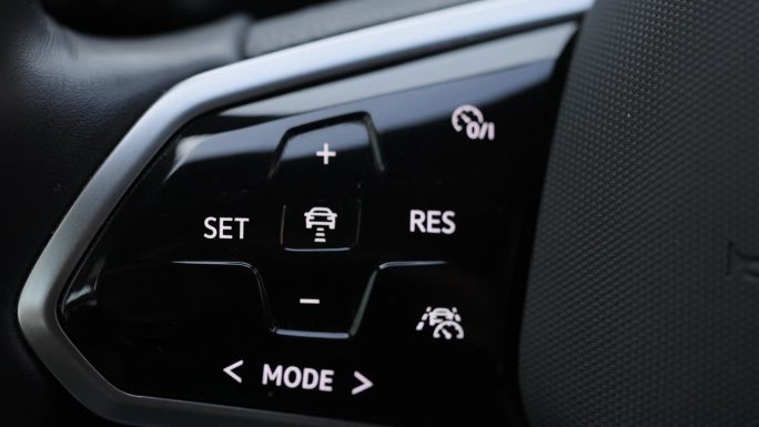 手指按下按钮启动自动巡航控制自动驾驶仪。自动驾驶汽车使用传感器，导航与交通感知巡航控制和自动驾驶