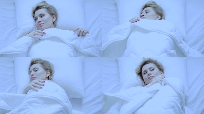 孤独不安的女人躺在床上，盖着毯子，想睡觉，感觉恶心和孤独，好像没有人在乎