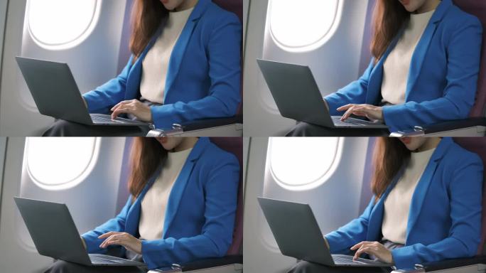 亚洲年轻女性坐在飞机头等舱靠窗的位置使用笔记本电脑，旅游和商务概念