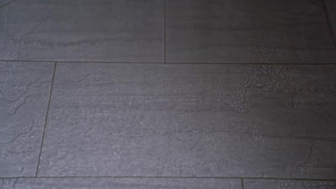 瑞士小镇家中以水滴落在淋浴器陶瓷地板上的特写。