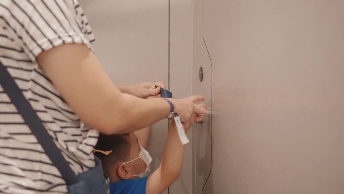 一位亚洲母亲带着她的儿子用钥匙卡打开防盗门。