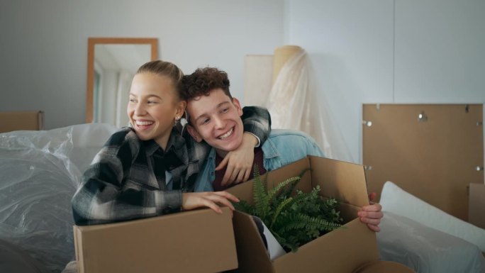 一对兴高采烈的年轻夫妇在他们的新公寓里搬着箱子。移动的概念。