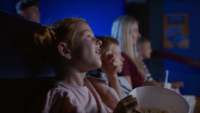 妈妈带着开心的小孩子在电影院，看电影。