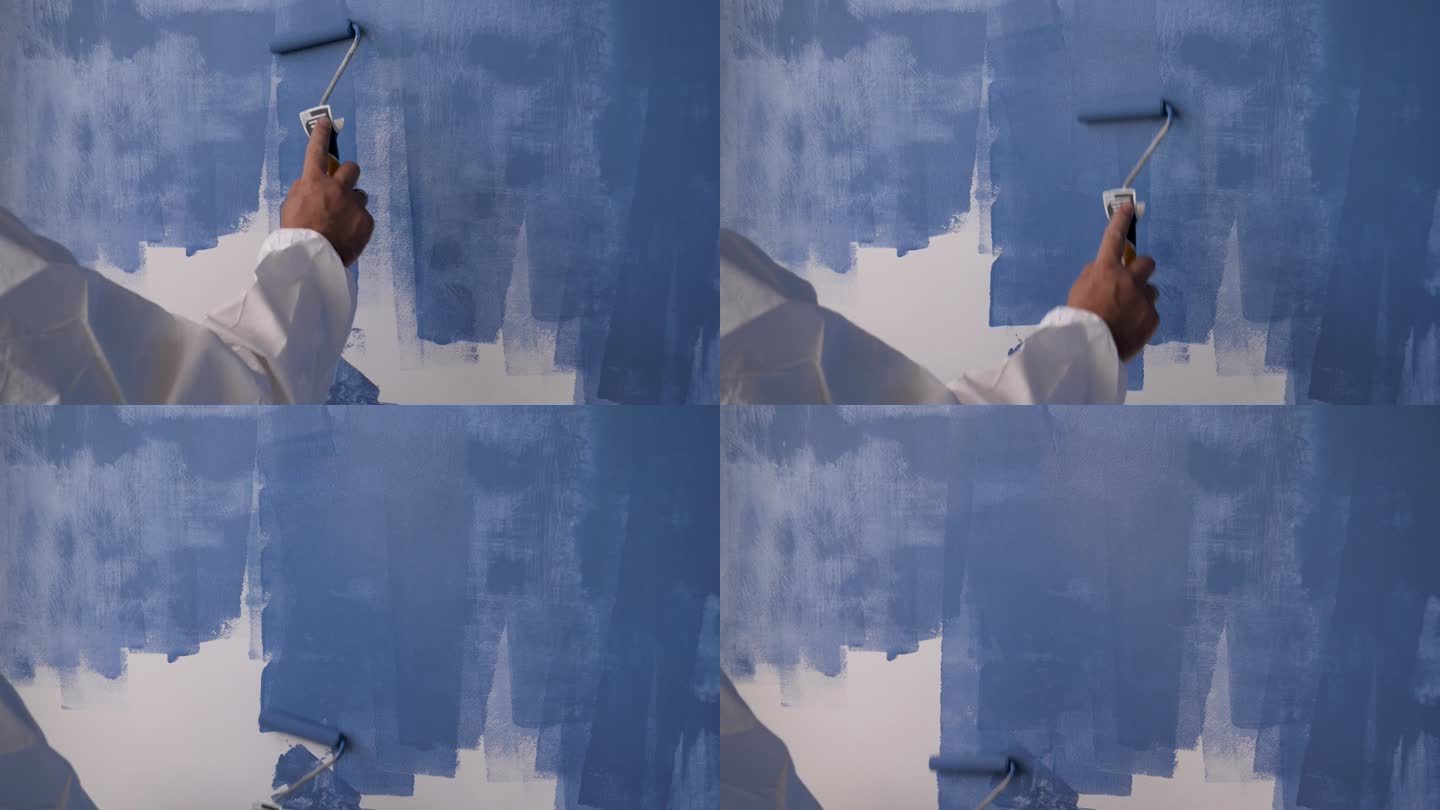 油漆工用蓝漆粉刷白墙的特写