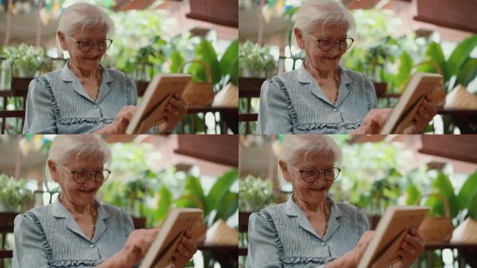 亚洲上了年纪的老奶奶在家里放松时看着家人的照片。慈爱的老祖母。老年人老年生活方式，老年人休闲理念