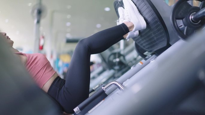 低段手持女子在健身房做腿推练习