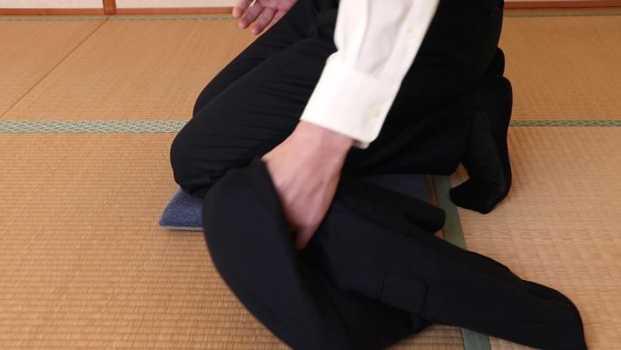 一个穿西装的男人坐在靠垫上，夹克在一边