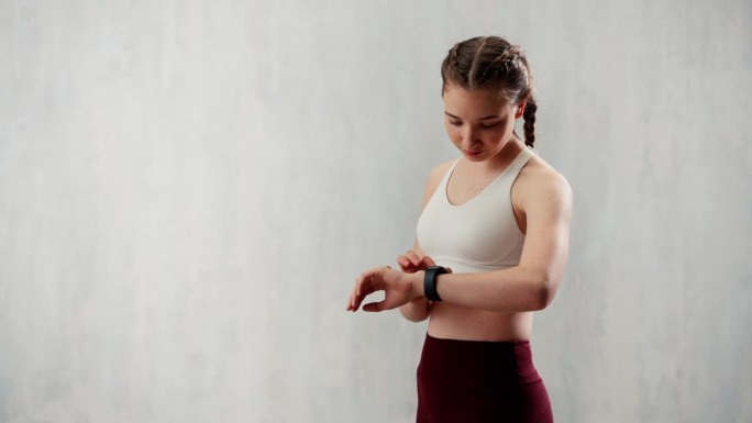 年轻女子设置和看运动智能手表。健身女检查她的表现。