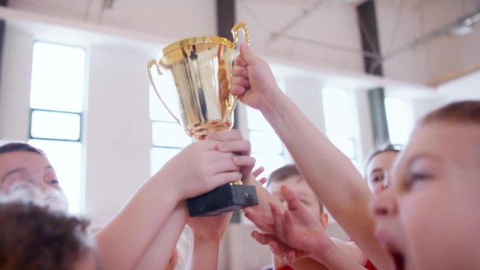 学校体育队员在室内体育比赛中获胜后举起金质奖杯。