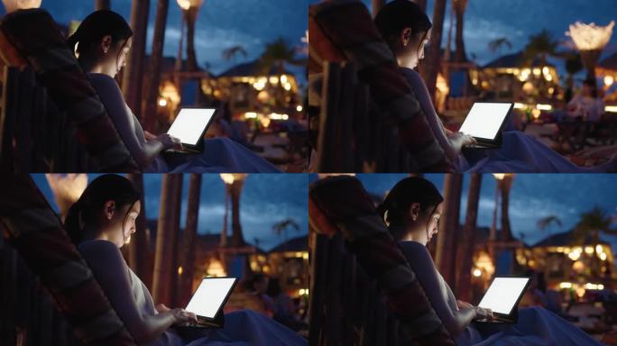 年轻的女自由职业者游客在晚上使用她的笔记本电脑