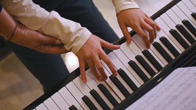 俯视图一位音乐老师，音乐家钢琴家握着一个小男孩的手，给学生上钢琴课