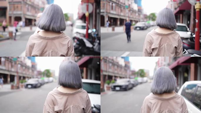 慢动作视频，一个年轻的台湾女人与白发漫步在迪化街的老街。