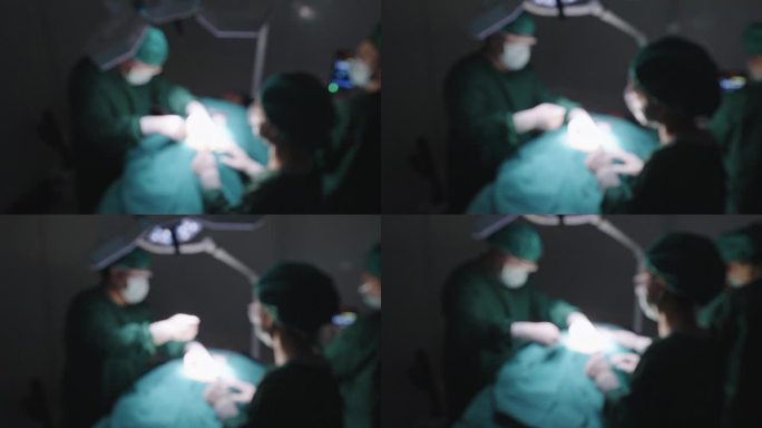 在医院的手术室里，包括外科医生、护士和助理在内的手术团队在手术过程中协同工作的散焦、高角度照片。