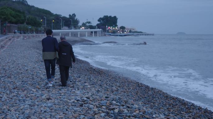 和老人在海边坐着散步交流