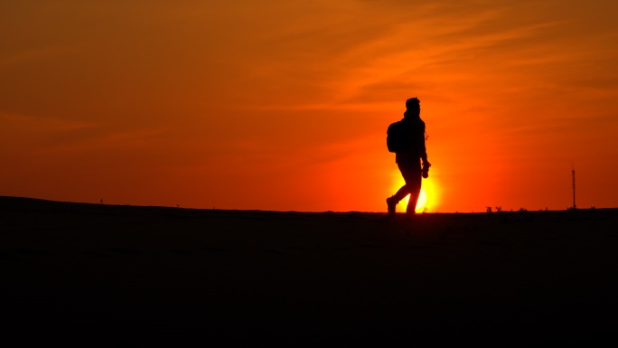 夕阳下人物在沙漠里逆光行走