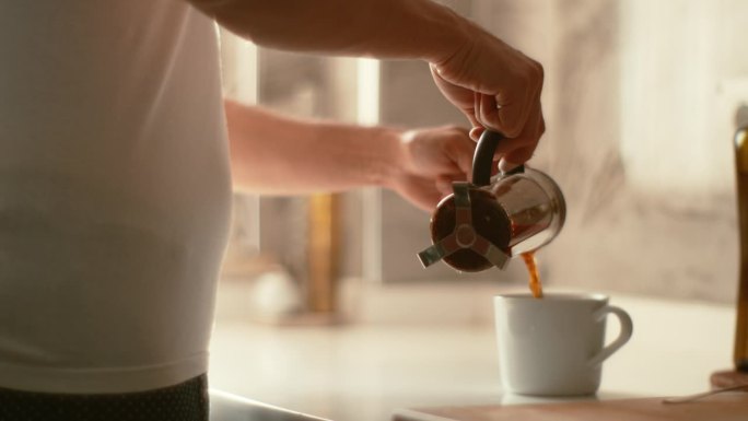 一名男子在厨房柜台上用法式压力锅煮红茶或早咖啡