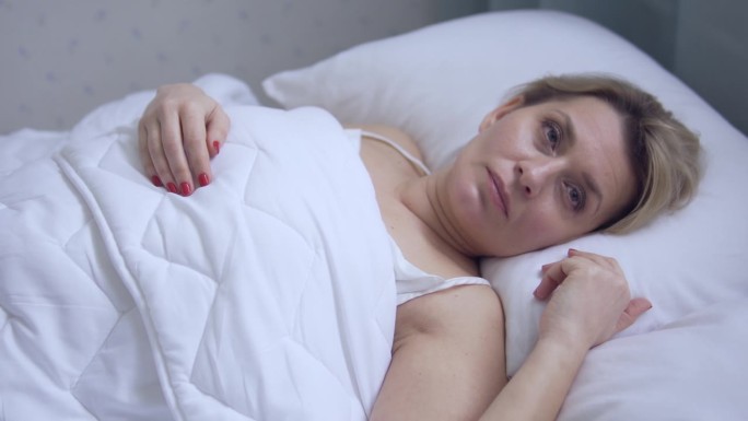 患有睡眠相障碍的妇女躺在床上睡不着觉，坐立不安