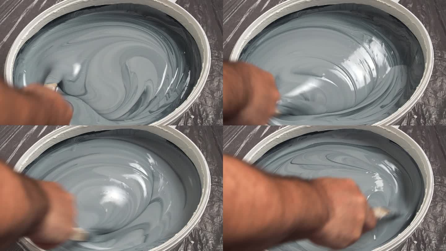 一个工人在桶里混合颜料来粉刷墙壁。