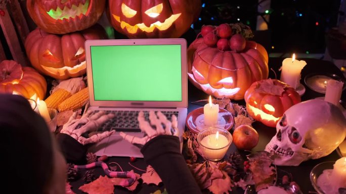 令人毛骨悚然的骷髅在笔记本电脑上键入邀请，绿色色度键屏幕邀请朋友聚会令人毛骨悚然的庆祝万圣节快乐