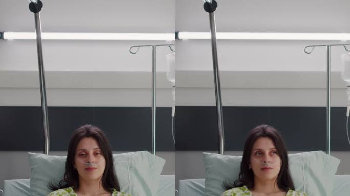 垂直视频:患者戴鼻吸氧管，坐在床上看着摄像头