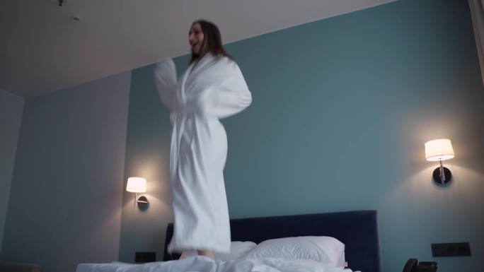 一位身穿白袍的美女跳上酒店房间的床