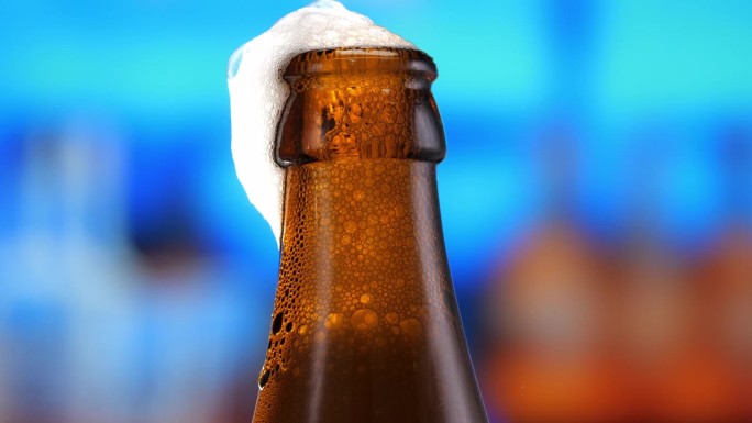 啤酒在啤酒瓶中，形成气泡和泡沫的头部。啤酒泡沫顺着瓶口流下来。特写镜头，微距镜头。啤酒抓住了啤酒节庆
