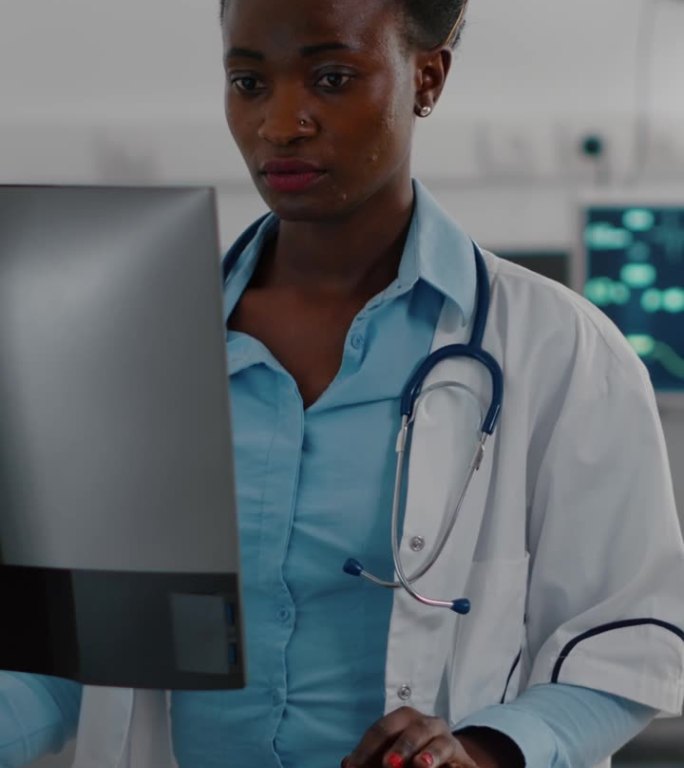 垂直视频:非裔美国医生在电脑上输入医学专业知识的正面视图