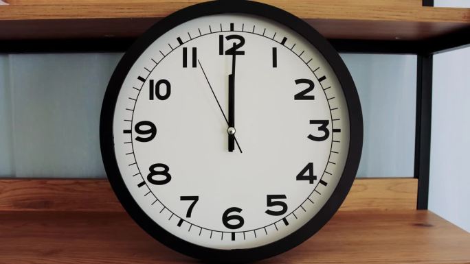白色壁钟上的白色钟面特写，箭头显示12:00或00:00