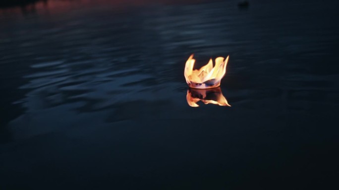 SLO MO燃烧折纸船漂浮在河与涟漪的夜晚