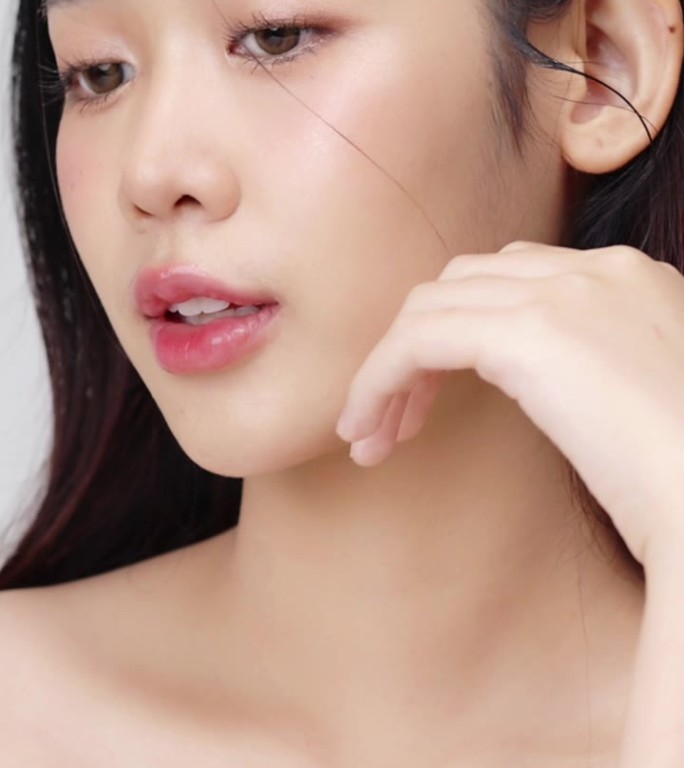 近距离的年轻美丽的年轻亚洲妇女的脸，健康和新鲜的皮肤。垂直美容镜头。