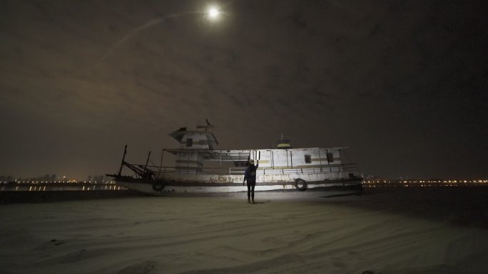 女生在天兴洲废弃的旧船旁玩无人机光绘摄影