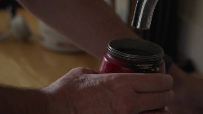 手放红炉子的特写，把浓缩咖啡壶放在水槽下面装满水