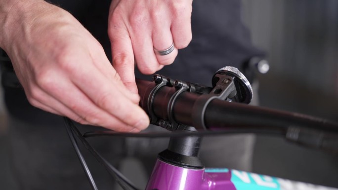 将车把固定在车杆上的过程，由自行车修理工用手轻轻转动螺丝。特写镜头,细节