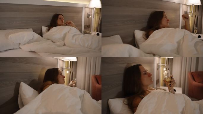 一个年轻的女人躺在床上，我走近她，她拿了一杯香槟，一边在酒店房间里看电视，一边喝着。