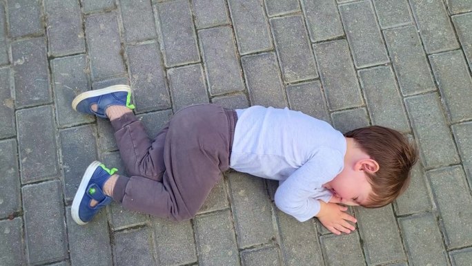 一个任性的孩子躺在地上哭着不肯走。两岁婴儿(两岁男童)