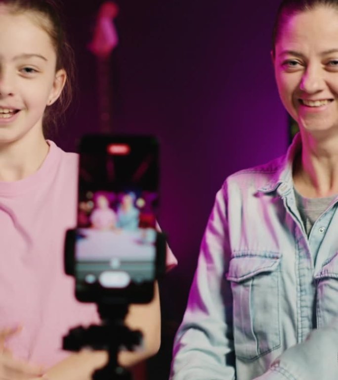 垂直视频小女孩和她的妈妈在家庭频道记录对网络剪辑的反应