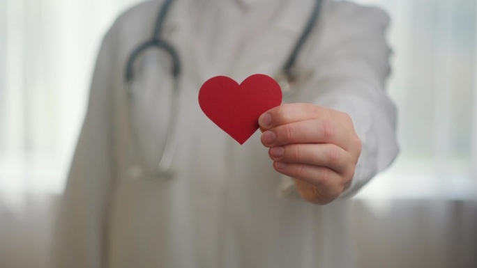 医院里不知名的年轻女医生，穿着白色制服，听诊器拿着红色的小心脏。爱，捐赠，世界心脏日，世界卫生日，企