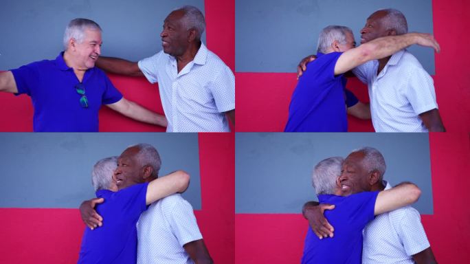 两个不同肤色的老年人站在街上互相拥抱。一个黑人老人拥抱他的白人朋友，描绘老年友谊