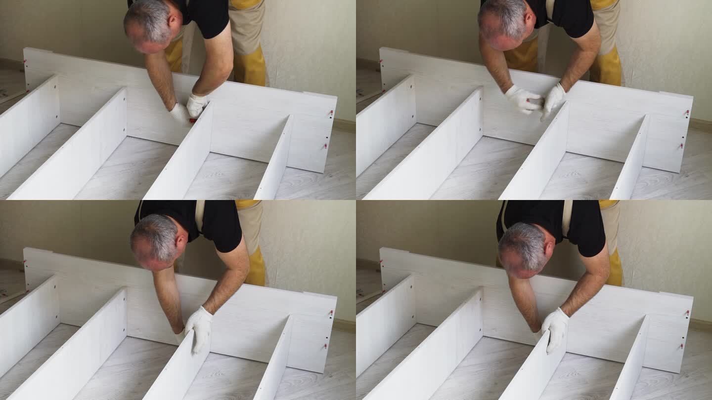 一名工人正在用拉链和螺丝刀把床的各个部件连接起来。