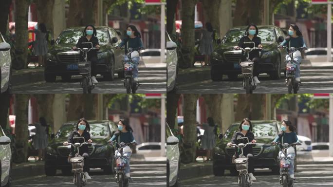 两个女人在马路上骑电动车