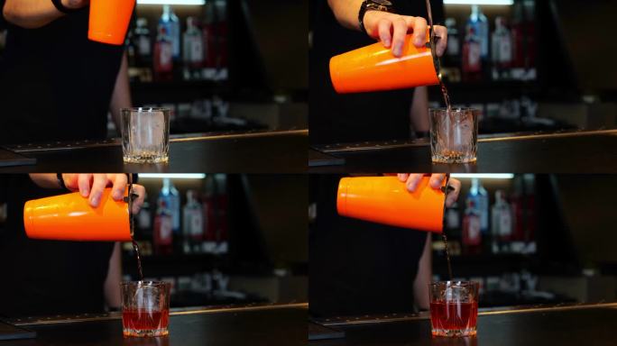酒保将新鲜的酒精饮料倒入柜台上装有冰块的玻璃杯中。裁剪。真正的时间。