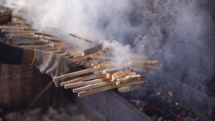 一个女人正在木炭上烤鲣鱼金枪鱼肉。海鱼沙爹