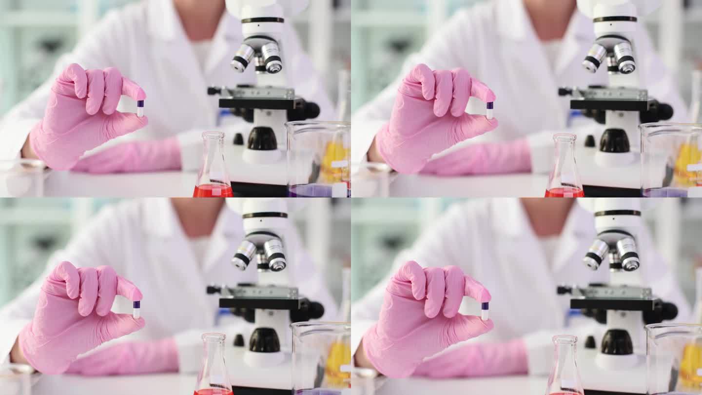 医生或科学家的手在显微镜下观察药片或药物